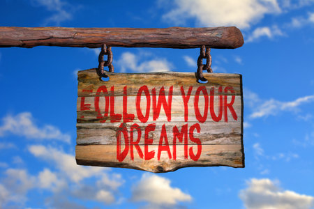 Follow your dreams motivational phrase sign on old wood with blurred backgroundの写真素材