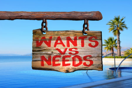 Wants vs needs motivational phrase sign on old wood with blurred backgroundの写真素材