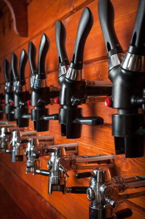 Beer taps for draft drinks are built into wooden boardsの写真素材
