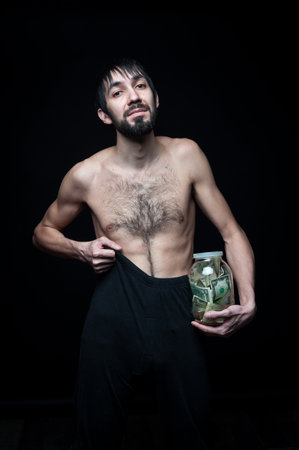 Young man with money bottle on black backgroundの写真素材