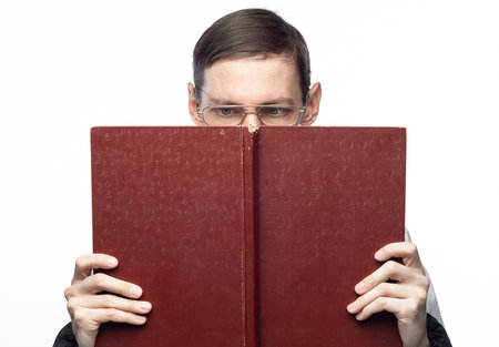 The man's face is covered by a large red notebook, on an isolated backgroundの写真素材