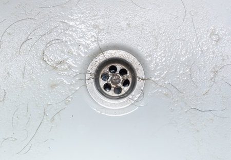 Dirty wash hand basin showing grungy drain with bits of hairの写真素材