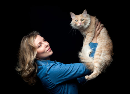 Beautiful proprietress posing with her cat on a black backgroundの写真素材