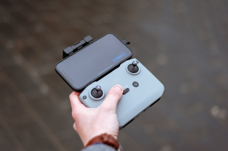 Remote control of the quadcopter. The operator controls the drone. The phone on the remote control. Quadrotor filming. Fingers on the joystick controlの写真素材