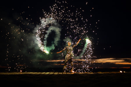 A girl lights a sparkler on the beach at duskの写真素材