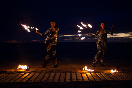 Two girls light a sparkler on the beach at duskの写真素材