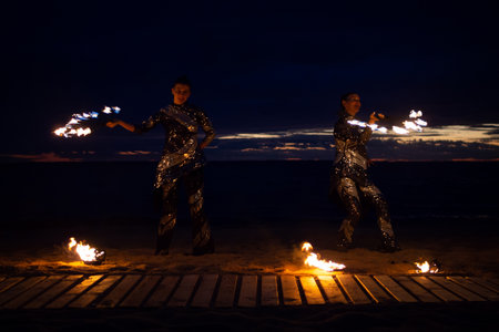 Two girls light a sparkler on the beach at duskの写真素材