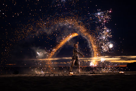 A girl lights a sparkler on the beach at duskの写真素材
