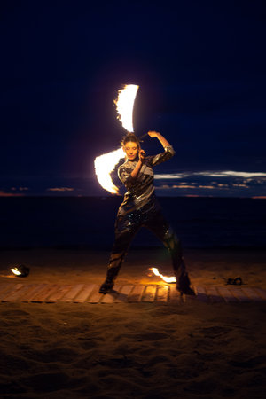 A girl lights a sparkler on the beach at duskの写真素材