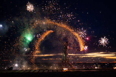 A girl lights a sparkler on the beach at dusk