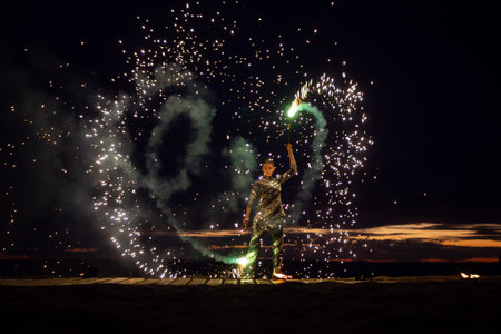 A girl lights a sparkler on the beach at duskの写真素材