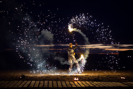 A girl lights a sparkler on the beach at duskの写真素材