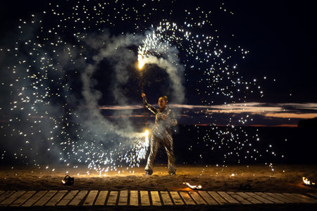 A girl lights a sparkler on the beach at duskの写真素材