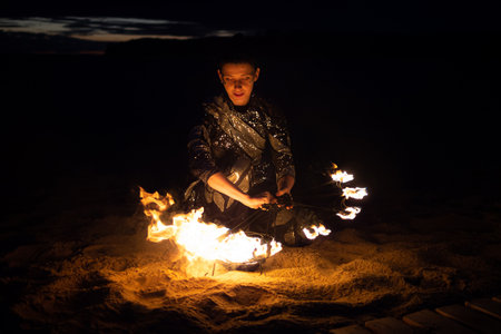A girl lights a sparkler on the beach at duskの写真素材