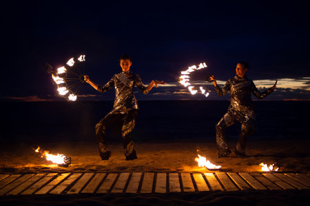 Two girls light a sparkler on the beach at duskの写真素材