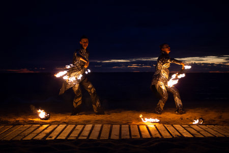 Two girls light a sparkler on the beach at duskの写真素材