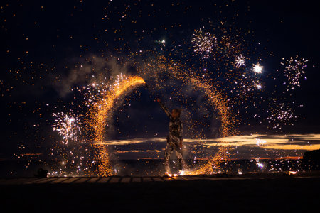 A girl lights a sparkler on the beach at duskの写真素材