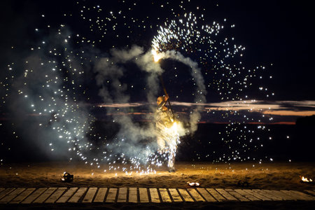 A girl lights a sparkler on the beach at duskの写真素材