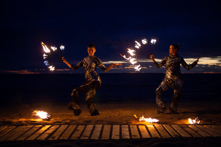 Two girls light a sparkler on the beach at duskの写真素材
