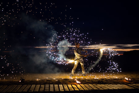 A girl lights a sparkler on the beach at duskの写真素材