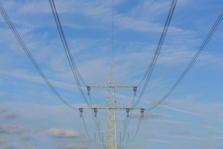 Background with electricity lines and high voltage in front of blue sky with cloudsの写真素材