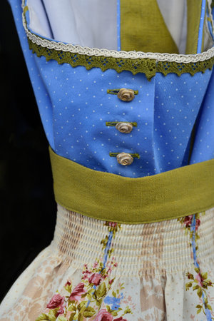 Close-up of a traditional blue Dirndels in Bavaria with ribbons and decorative buttons as well as...