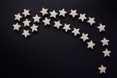 A big Christmas star made of many little biscuits in star shape, against a dark background with...
