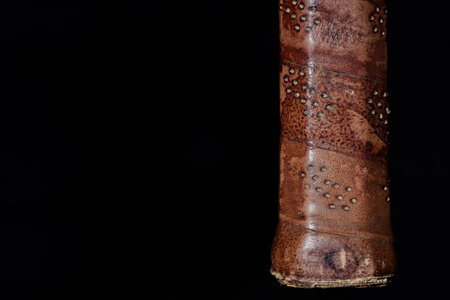 Closeup and detail shot of an old handle wrapped in old leather against a dark background with...