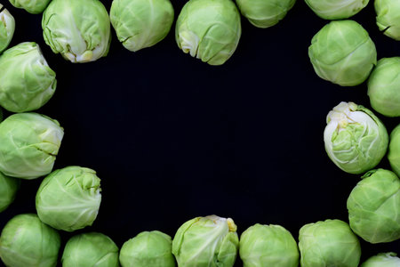 A black background with a frame of fresh Brussels sprouts showing the green vegetablesの写真素材