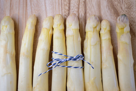 White fresh raw asparagus lie side by side on a wooden surfaceの写真素材