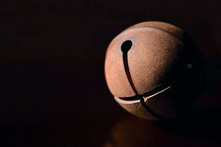 A round bell made of old metal against a dark background