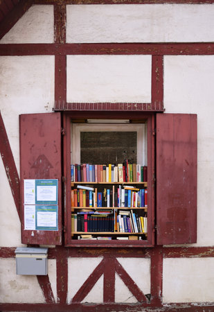 A small open library during the corona pandemic in Augsburg offers books in a historic half-timbered house at an open window.のeditorial素材