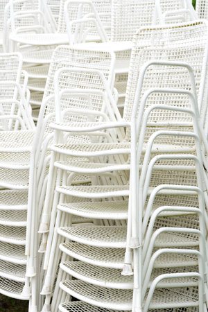 Many used white metal chairs are piled up waiting to be usedの写真素材
