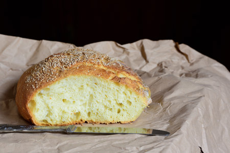 Close up of a sliced â€‹â€‹white bread with sesame seeds on a piece of paper against a...