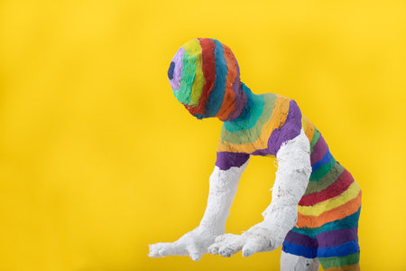 A stylized figure made of plaster is painted with different colors. The figure has no face. The stripes are rainbow colors. Man is searching.のeditorial素材