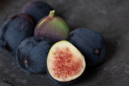 Close up of several dark figs lying on an old metal plate. A fig is cut open.の写真素材