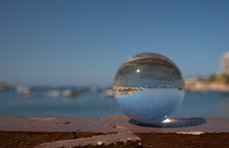 In a glass sphere, which stands in the foreground on a stone wall, you can see the sea and the coast...