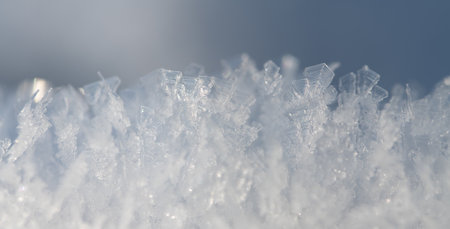 Close-up of ice and snow crystals shining in the soft, bright light. The background is light-colored and there is space for text.の写真素材