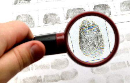comparing the fingerprint through the dactyloscopic magnifier glassの写真素材