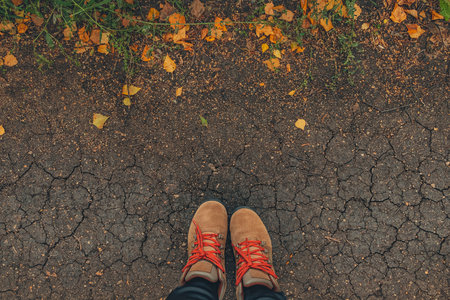 Casual unisex boots with bright laces and colorful autumn fallen leaves. Autumn fall scene. Conceptual image of legs in boots on dry earth and autumn leaves. Lifestyle Fashion trendy style. Top view.の写真素材