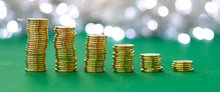 Banner with stacks of coins on blur background. Stacks of gold money coins on green background with...