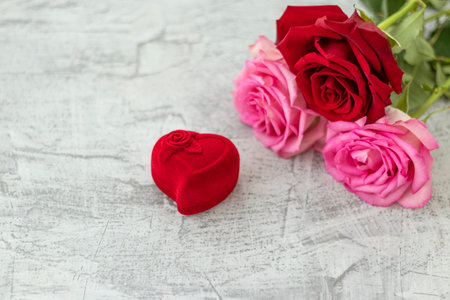 Red velvet box for engagement ring next to a bouquet of roses with space for text .Romantic gift for valentines day. Marriage proposal concept. Soft focus. Copy spaceの写真素材