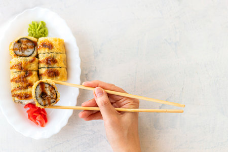 Japanese sushi food on white background with copy space. Female hand holding sushi. Top view of sushi in white plate. Soft focusの写真素材