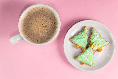 Cup of coffee and homemade cookies in the shape of a Christmas tree on a pastel pink color. New Year's or Christmas breakfast. Merry Christmas or Happy new year concept. Soft focusの写真素材