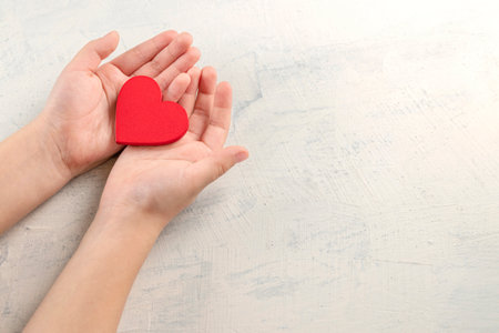 Hands holding red heart on white background. Health care, love, organ donation, mindfulness, wellbeing, family insurance and CSR concept, world heart day, world health day, National Organ Donor Day.の写真素材