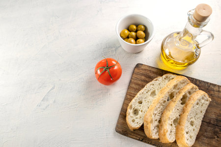 Fresh, tasty focaccia serving option. Sliced bread on a blackboard with olives, tomato and olive oil...