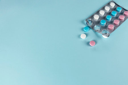 Medicines and pills. Blue, pink and white pills. Multicolored medicines on a pastel blue background....