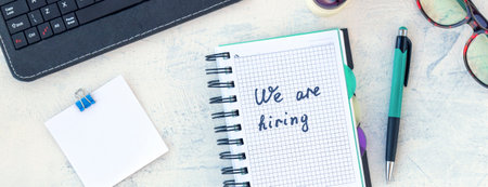 Banner with words We are hiring. Job recruiting concept. Words We are hiring in notebook on the working table. Top view.の写真素材