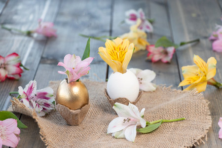 alstroemeria flower in an egg on a wooden background with flowers. Happy Easter concept. Soft focusの写真素材