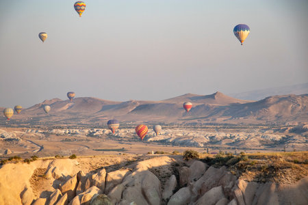 Turkey, Cappadocia, Goreme, August 1, 2019. Multicolored balloons in the sky above the sandy mountainsの写真素材